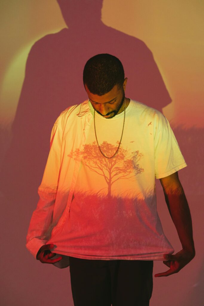 pexels-photo-7541670-7541670 A man observes a tree graphic projected onto his shirt, creating a unique shadow effect.